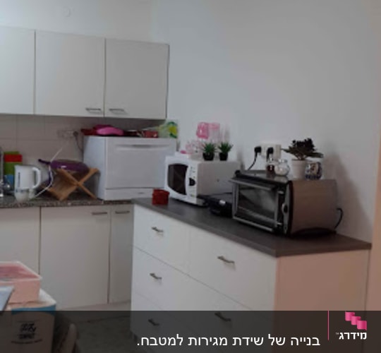 מטבח עם ארונות לבנים, מיקרוגל וטוסטר על השיש